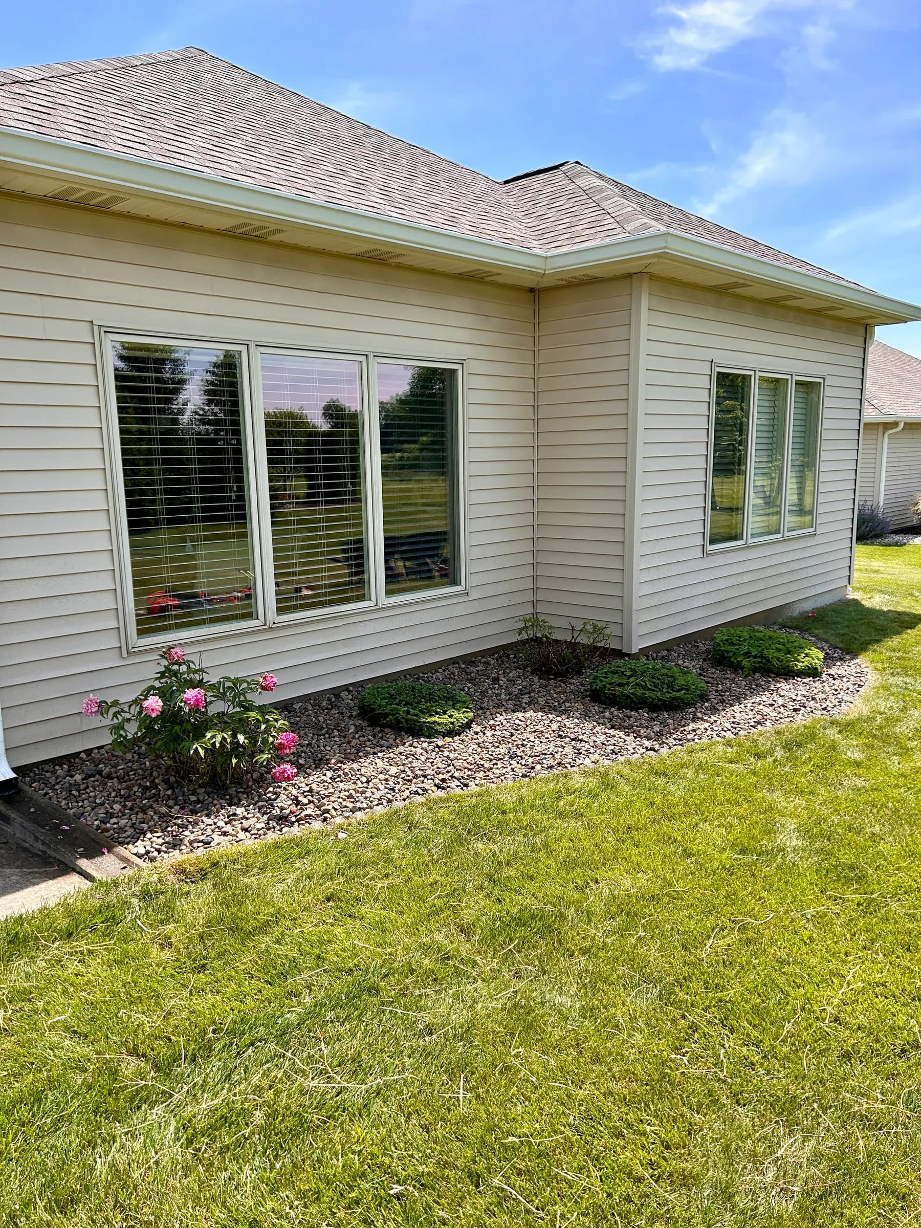 A river rock planting bed with shrubs along a home