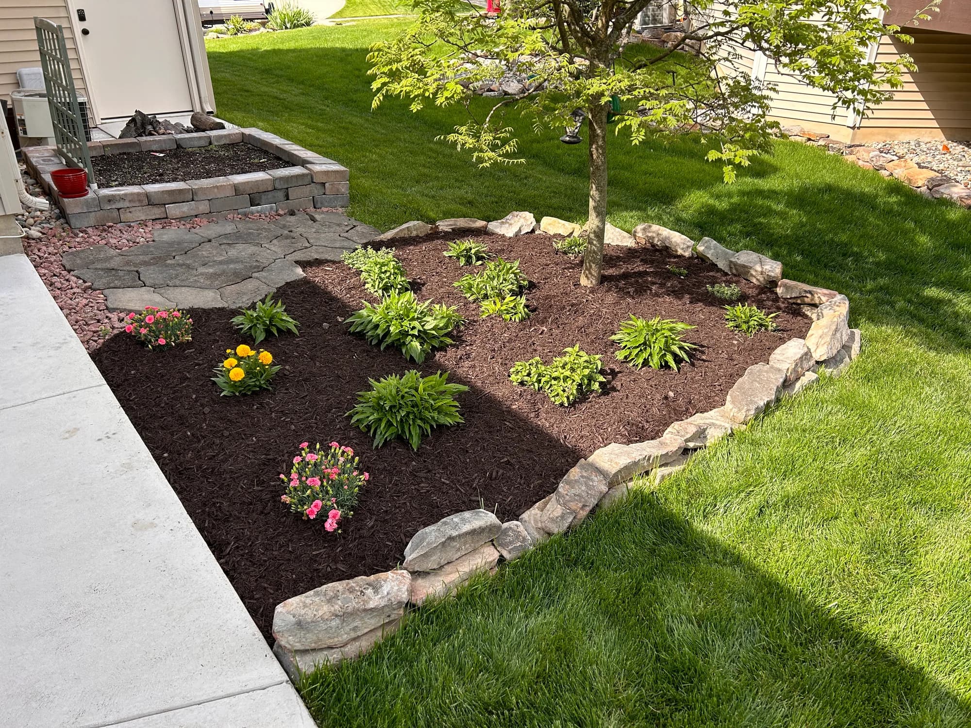 Fresh mulch and flowers inside a natural stone garden border