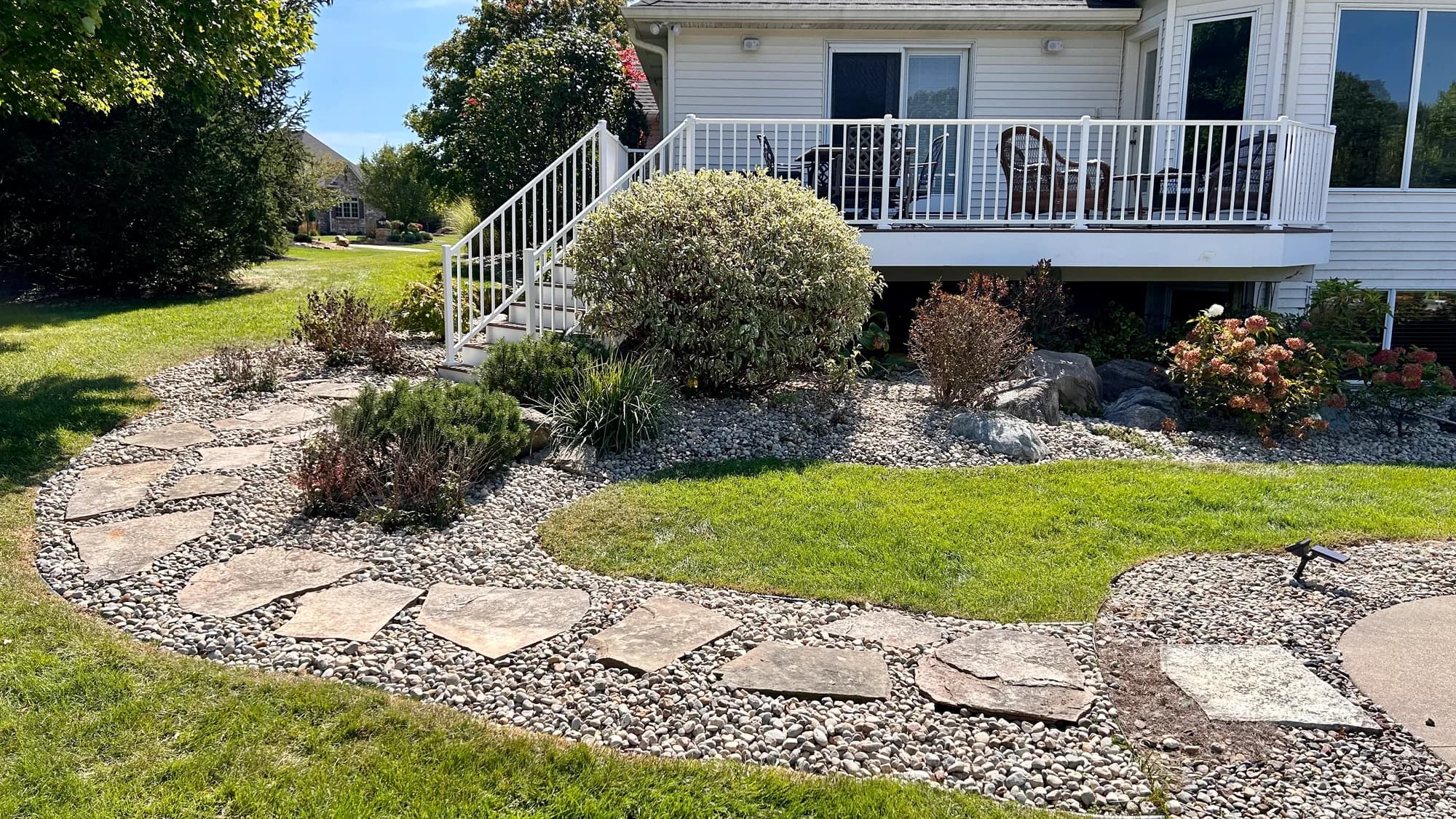 River rock landscape beds and a stone walkway around a maintained home